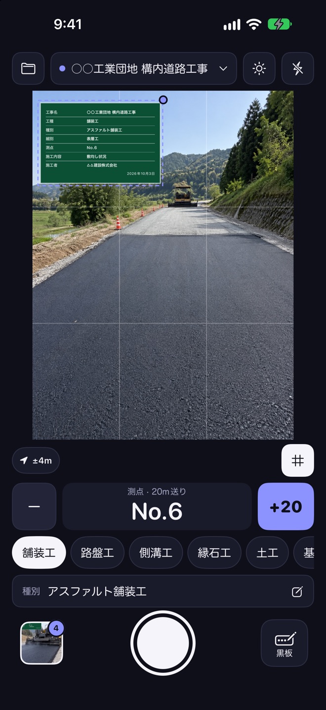撮影画面。舗装中の道路の写真の左上に、工事名・工種・測点を書いた緑の黒板が重なっている